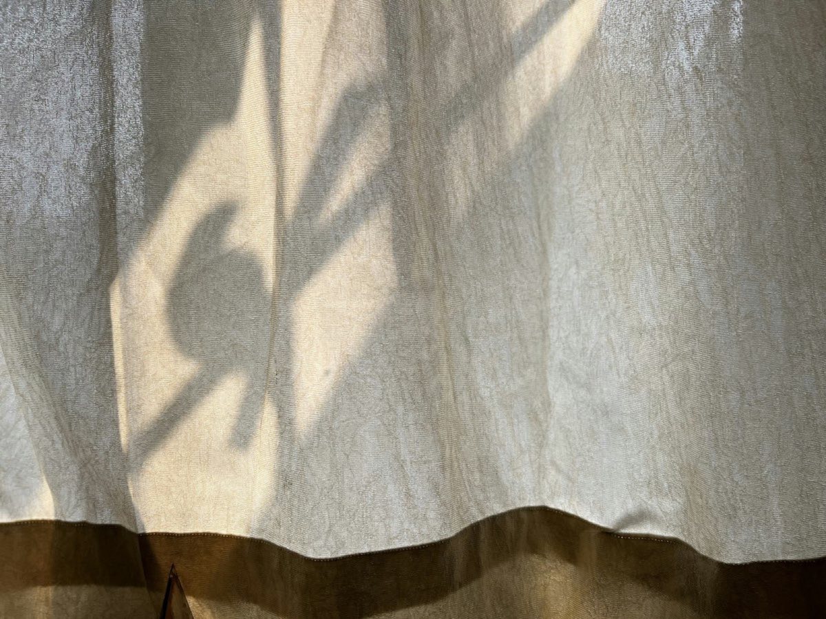 Leinenvorhang, durch den weiches Sonnenlicht mit Pflanzenschatten fällt